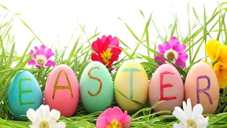 Picture of grass and Spring flowers with pastel colored eggs spelling out Easter