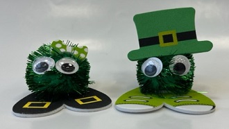 green pom-poms with googly eyes and either a green bow or green top hat